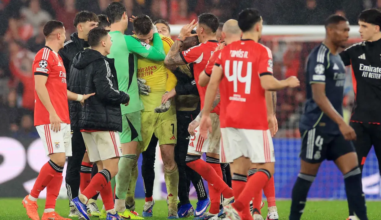 Penjaga gawang Real Madrid asal Belgia, Thibaut Courtois memeluk kiper Benfica asal Ukraina #01 Anatoliy Trubin (C) di akhir pertandingan pekan ke-8 Liga Champions 2025-2026 di Estadio da Luz, Lisbon, Rabu (28/1/2026) waktu setempat atau Kamis (29/1/2026) dini hari WIB. (PATRICIA DE MELO MOREIRA/AFP)