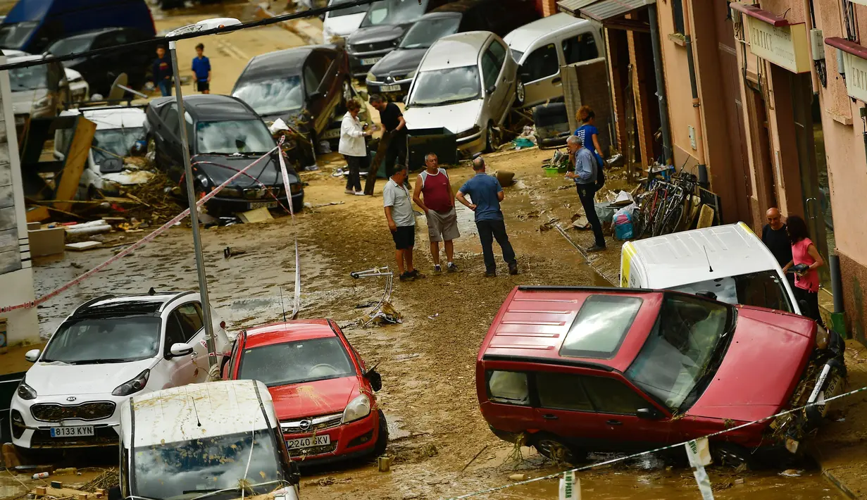 Warga berkumpul di jalan dekat mobil yang rusak setelah banjir bandang menerjang Tafalla, Spanyol, Selasa (9/7/2019). Hujan deras menyebabkan dua sungai meluap dan menimbulkan banjir bandang. (AP Photo/Alvaro Barrientos)