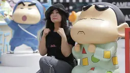 Seorang wanita berekspresi sedih mengikuti model Crayon Shinchan saat berfoto di pameran Joy City, Beijing (5/5/2015). Lima puluh model karakter kartun Jepang dalam berbagai pose dan ekspresi dihadirkan dipameran tersebut. (REUTERS/Jason Lee)