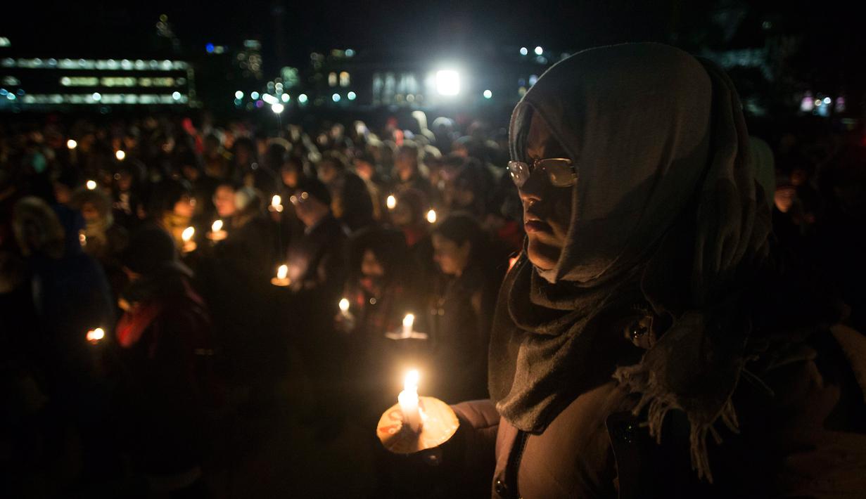 Seorang wanita ikut bergabung menyalakan lilin dalam aksi dukungan pada komunitas muslim di Toronto, Senin (30/1). Dukungan itu setelah aksi penembakan di sebuah masjid di Kota Quebec, Kanada yang menewaskan 6 orang (Chris Young/The Canadian Press via AP)