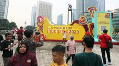 Masyarakat berswafoto dengan latar belakang papan promosi Piala Dunia U-17 2023 saat car free day (CFD) di kawasan Jalan Thamrin, Jakarta, Minggu (15/10/2023). Kegiatan tersebut dalam rangka promosi ajang Piala Dunia U-17 2023 di Indonesia. (Liputan6.com/Faizal Fanani)