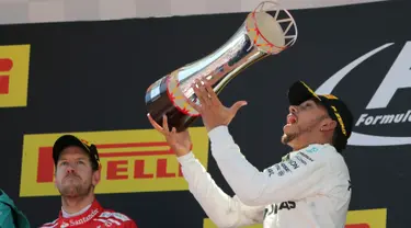 Pembalap Mercedes, Lewis Hamilton merayakan kemenangannya pada balapan F1 GP Spanyol di atas podium Sirkuit Catalunya, Minggu (14/5). Hamilton yang start dari posisi pole menyelesaikan 66 lap dengan gemilang. (AP Photo/Emilio Morenatti)