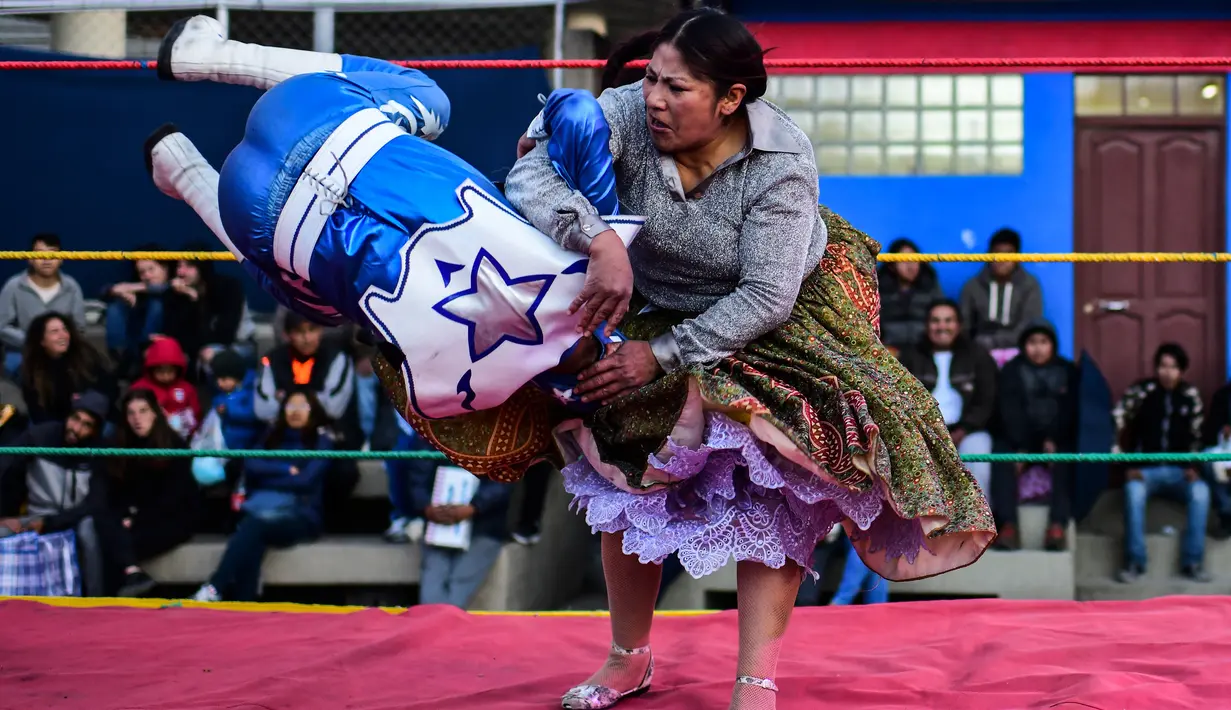 Pegulat Bolivia, Ana Luisa Yujra (kanan) membanting lawannya pegulat pria di atas ring gulat di El Alto, pada 24 November 2019. Di Bolivia ada sebuah atraksi gulat yang diperankan perempuan dengan menggunakan busana khas warga Bolivia. (Ronaldo SCHEMIDT / AFP)