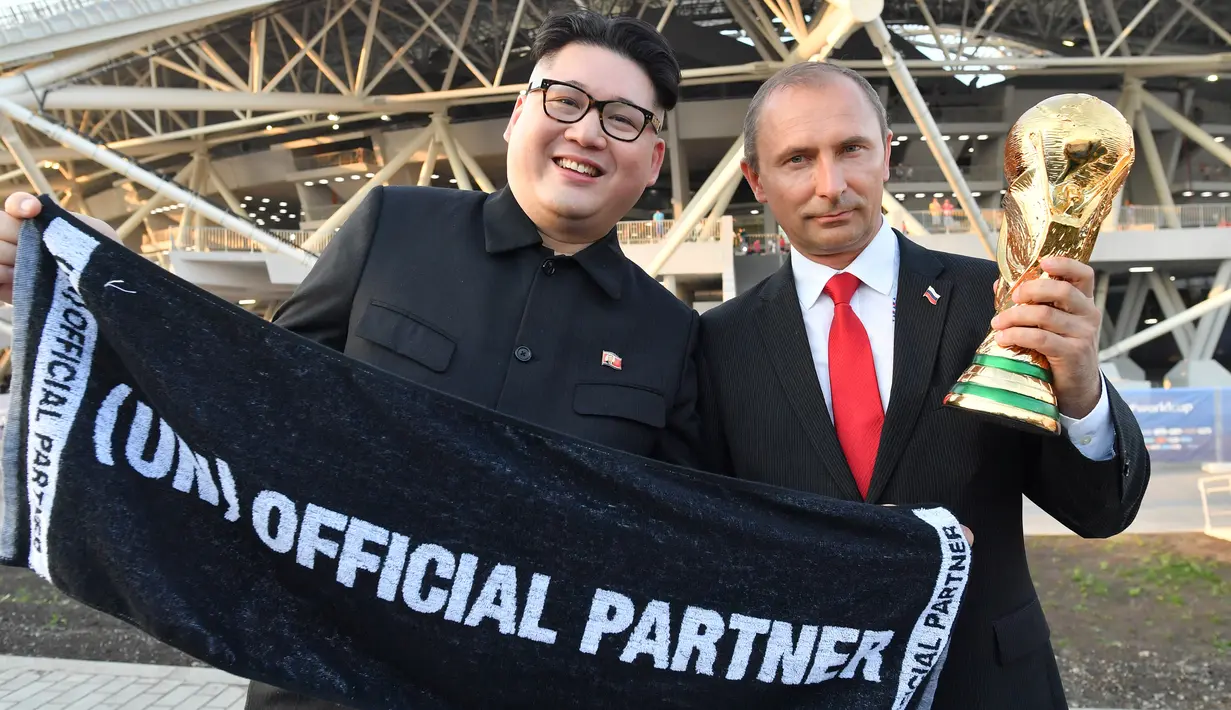Peniru Presiden Rusia, Vladimir Putin dan pemimpin Korea Utara, Kim Jong-un berpose dengan replika piala Piala Dunia usai penyisihan Grup A antara Uruguay vs Rusia di Samara Arena, Senin (25/6). Uruguay berhasil melumat Rusia 3-0. (AFP/EMMANUEL DUNAND)
