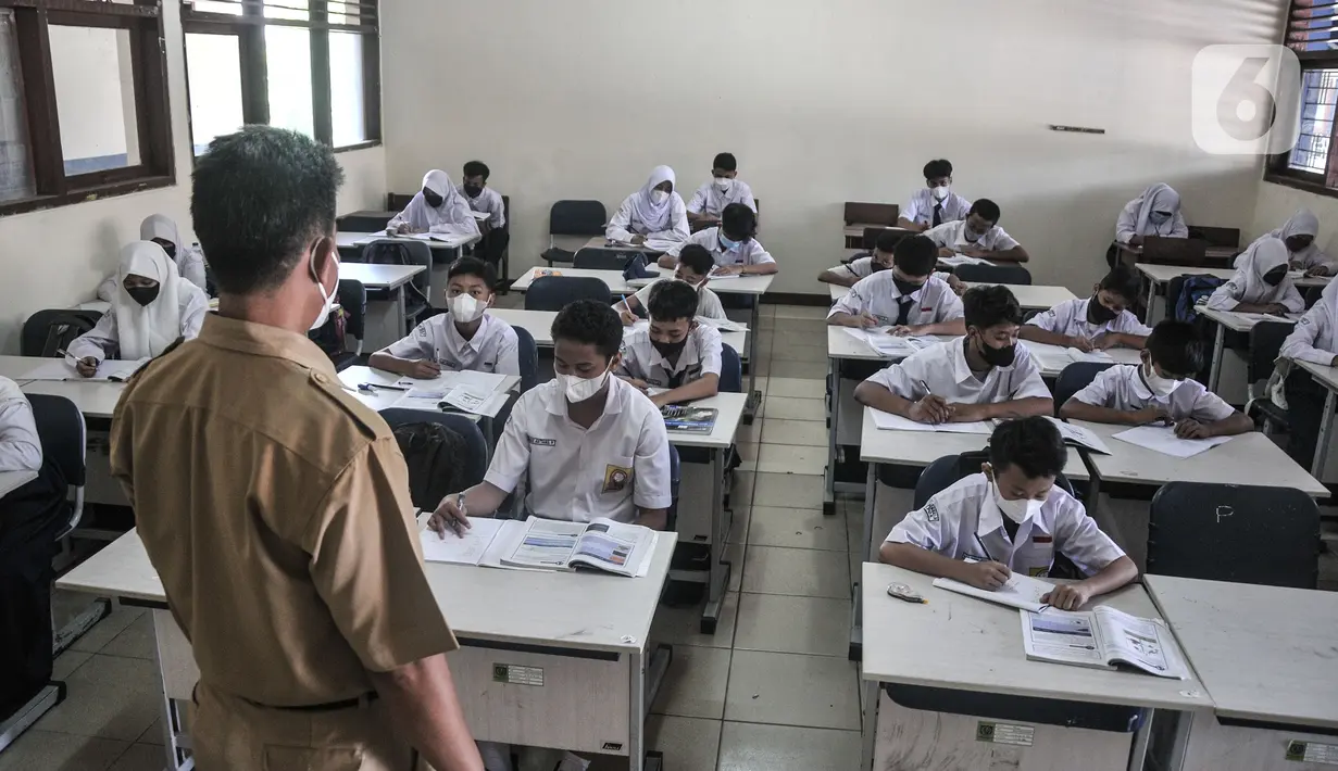 Guru mengawasi murid saat kegiatan Pembelajaran Tatap Muka (PTM) 100 Persen di SMP Negeri 9 Depok, Cipayung, Jawa Barat, Senin (24/1/2022). PTM 100 persen di Depok berlangsung selama 6 jam yang terdiri atas tiga mata pelajaran per hari. (merdeka.com/Iqbal S Nugroho)