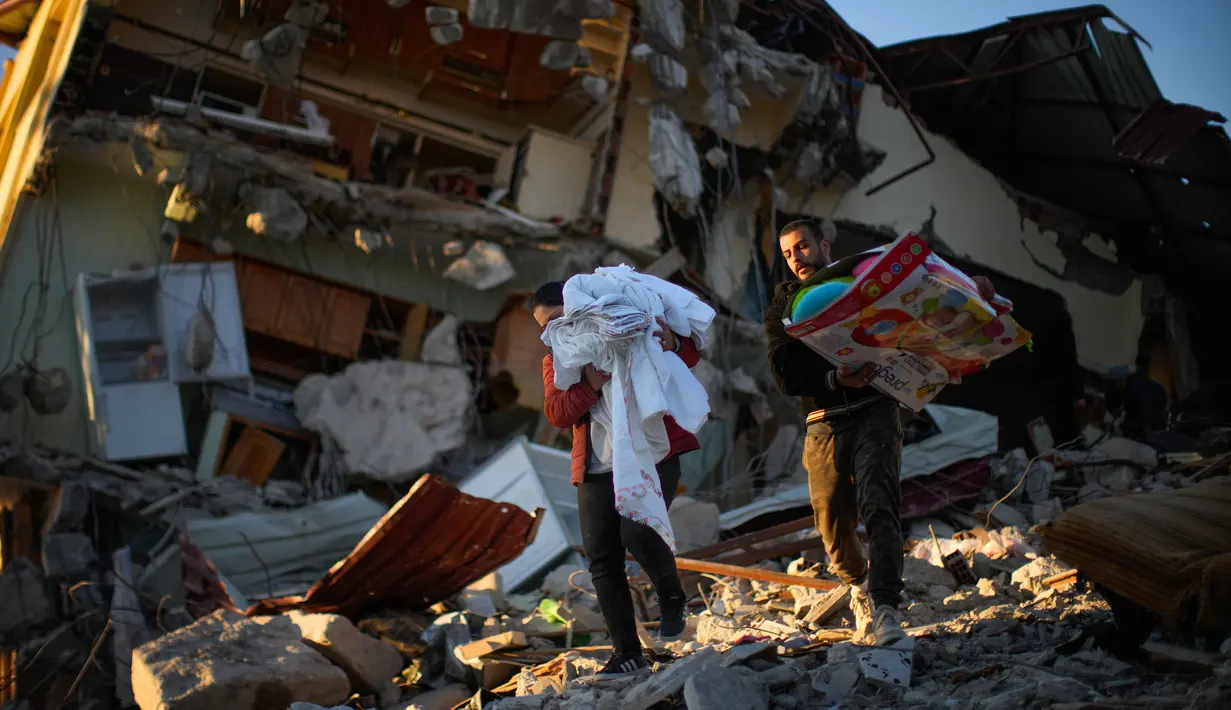 Warga memindahkan barang-barang dari rumah mereka yang hancur setelah gempa di Samandag, Turki, 16 Februari 2023. Otoritas Turki mengatakan setidaknya 38.044 orang telah tewas, sementara pemerintah Suriah dan PBB mengatakan lebih dari 5.800 orang tewas di sana. (AP Photo/Francisco Seco)