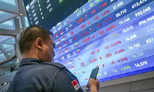 Seorang pria melihat ponselnya di depan layar yang menampilkan Indeks Harga Saham Gabungan (IHSG), yang anjlok signifikan selama pembukaan pasar, di gedung Bursa Efek Indonesia di Jakarta pada Rabu 13 Mei 2026. (BAY ISMOYO/AFP)
