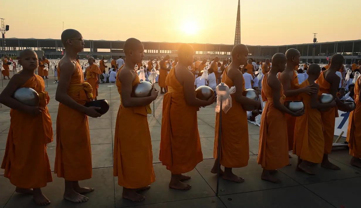 Sejumlah biksu muda berbaris untuk menerima sedekah usai melakukan ritual Makha Bucha Day di kuil Wat Dhammakaya, Bangkok, Thailand (11/2). (AFP/Lillian Suwanrumpha)