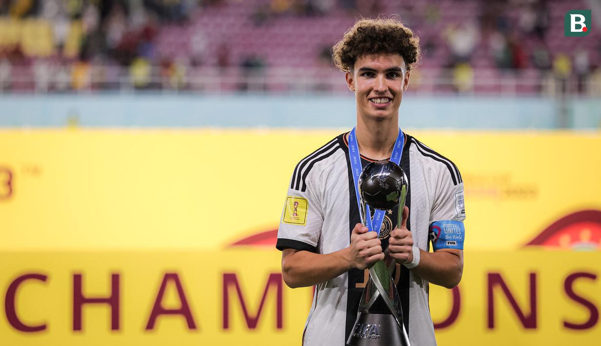 Kapten Timnas Jerman U-17, Noah Darvich menggenggam trofi Piala Dunia U-17 dalam perayaan gelar juara Piala Dunia U-17 2023 setelah mengalahkan Timnas Prancis U-17 lewat adu penalti pada laga final Piala Dunia U-17 2023 di Stadion Manahan, Solo, Sabtu (2/12/2023). (Bola.com/Bagaskara Lazuardi)