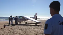 Petugas polisi memeriksa sebuah pesawat kecil yang mendarat darurat di pantai Sao Joao dekat Lisbon, Portugal, Rabu (2/8). Pria 56 tahun dan gadis delapan tahun tewas karena tak dapat menghindar saat pesawat itu mendarat darurat. (AP Photo/Armando Franca)
