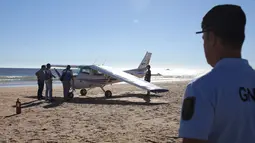 Petugas polisi memeriksa sebuah pesawat kecil yang mendarat darurat di pantai Sao Joao dekat Lisbon, Portugal, Rabu (2/8). Pria 56 tahun dan gadis delapan tahun tewas karena tak dapat menghindar saat pesawat itu mendarat darurat. (AP Photo/Armando Franca)