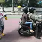 Petugas Srikandi Damkar Bandung sedang menyemprotkan cairan disinfektan kepada para pengendara kendaraan bermotor di Jalan Asia Afrika, Kota Bandung, Kamis (26/3/2020). (Humas Pemkot Bandung)