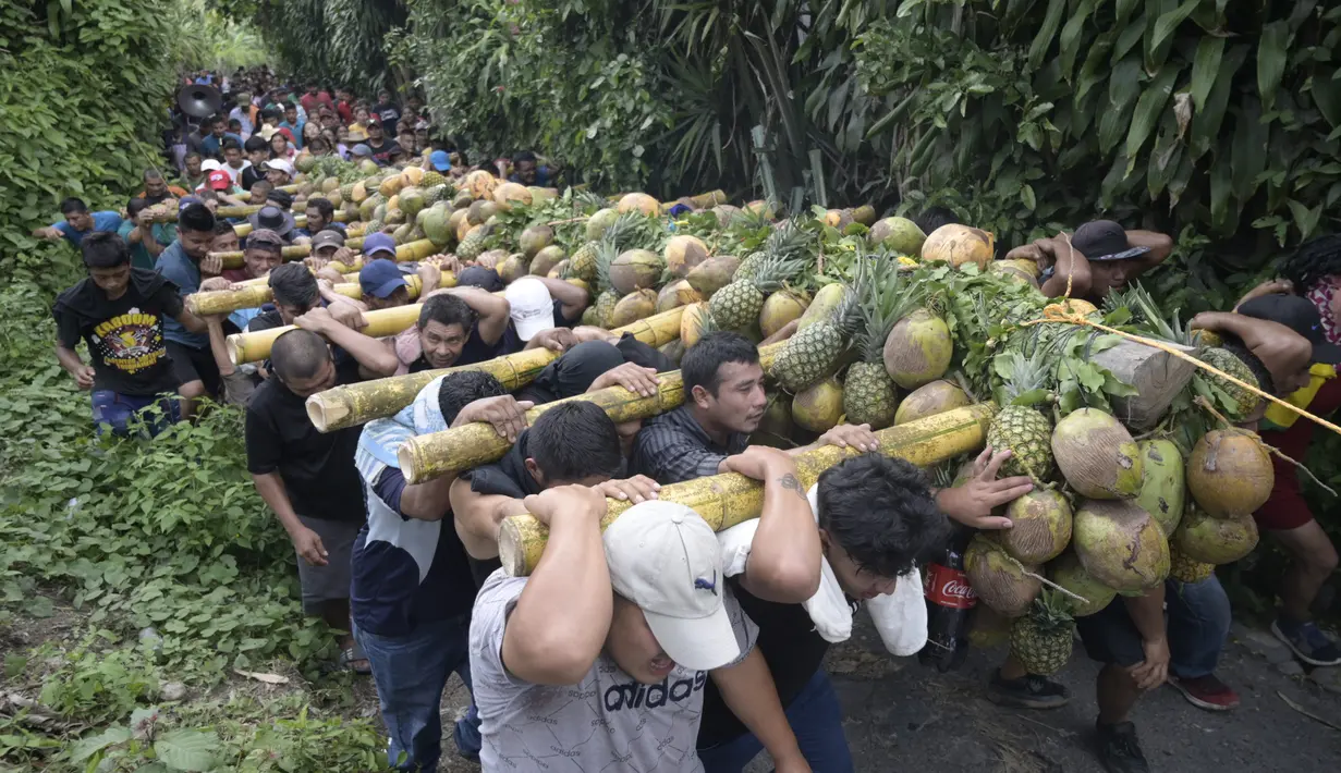 Laki-laki membawa seikat buah di tiang bahu selama perayaan Santa Cruz di Santa Maria Ostuma, 65 km timur San Salvador (31/5/2022). Ratusan orang Salvador membawa buah dengan yodes kayu berjalan melalui desa Santa Maria Ostuma di El Salvador tengah untuk berterima kasih kepada Salib Suci atas panen yang melimpah. (AFP/MARVIN RECINOS)