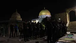 Warga Palestina melaksanakan salat Tarawih pertama di bulan suci Ramadan di kompleks Masjid Al-Aqsa, Yerusalem, pada Selasa 17 Februari 2026 malam waktu setempat. Tampak dalam foto, para jamaah Muslim Palestina melaksanakan salat Tarawih pada malam pertama bulan suci Ramadan di dekat Kubah Batu, kompleks Masjid Al-Aqsa, Kota Tua Yerusalem pada 17 Februari 2026. (AHMAD GHARABLI/AFP)