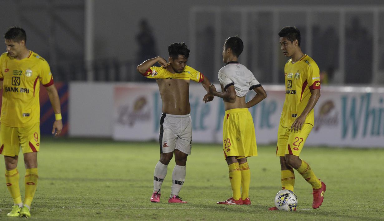 Gelandang Madura United, Andik Vermansah, bertukar jersey dan celana dengan gelandang Bhayangkara FC, Wahyu Suboseto, pada laga Liga 1 2019 di Stadion Madya, Jakarta, Senin (5/8). Kedua tim bermain imbang 1-1. (Bola.com/M iqbal Ichsan)