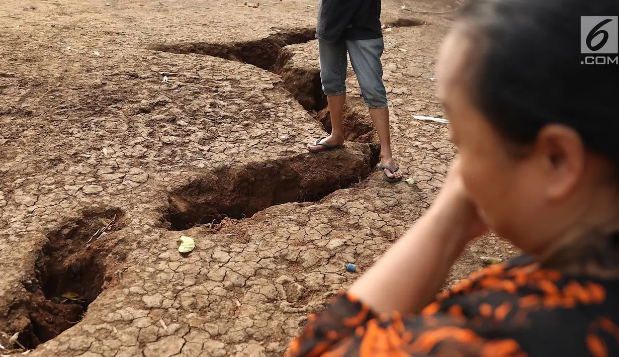 Warga mengamati tanah terbelah di lapangan RT 02 RW 02 Kampung Pedurenan, Kelurahan Cisalak Pasar, Cimanggis, Depok, Jawa Barat, Senin (22/10). Tanah terbelah tersebut kini dalam penyelidikan. (Liputan6.com/Immanuel Antonius)