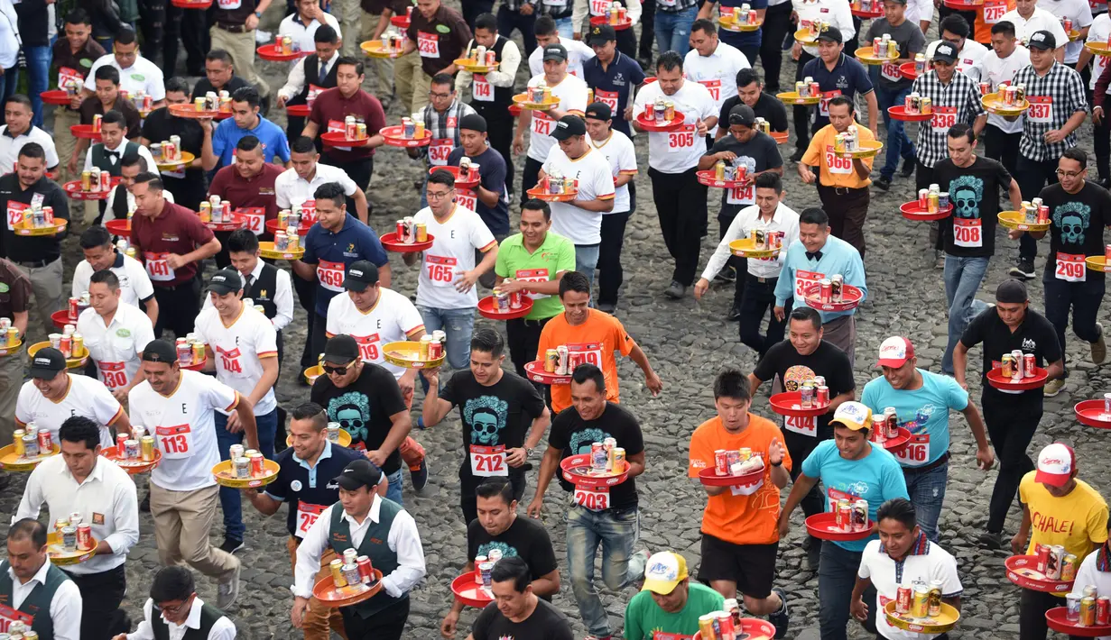 Pramusaji dari berbagai restoran berpartisipasi dalam Waiters Race ke-16 di Antigua, barat daya Ibu Kota Guatemala City, Rabu (14/11). Ratusan peserta beradu kecepatan sembari membawa nampan berisi dua minuman ringan, bir dan air. (JOHAN ORDONEZ/AFP)