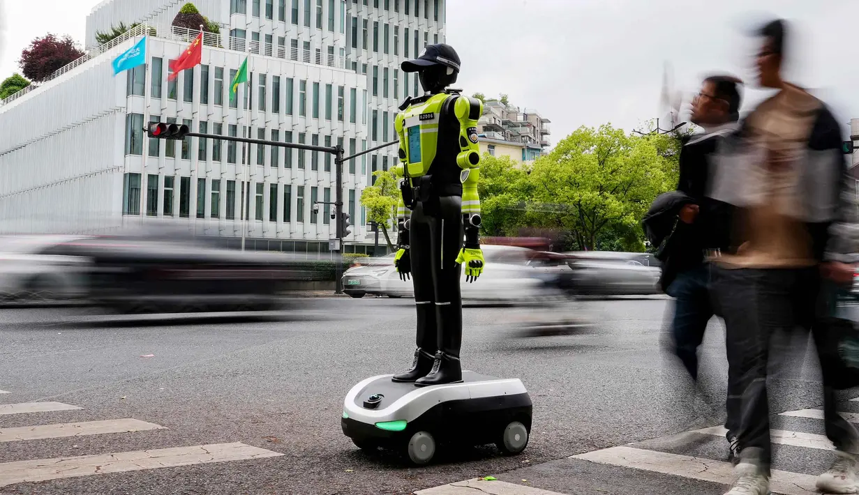 Orang-orang berjalan melewati robot polisi humanoid di Hangzhou, provinsi Zhejiang Timur, Tiongkok pada Minggu 3 Mei 2026. 15 robot humanoid dikerahkan di Hangzhou, Provinsi Zhejiang, Tiongkok. (Agatha CANTRILL/AFP)