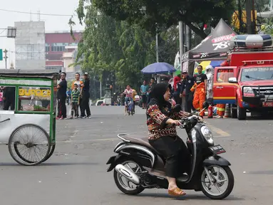 Pengendara motor melintasi arena Car Free Day (CFD) di Jalan Warung Jati Barat, Jakarta, Minggu (17/9).  Beberapa pengendara motor terlihat bebas menerabas jalan yang dipenuhi orang yang sedang berolahraga dan berjualan. (Liputan6.com/Immanuel Antonius)