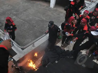 Seorang pria membakar diri dan terjun dari atap stadion Gelora Bung Karno, Jakarta, Jumat (1/5/2015). Sejumlah buruh tampak berusaha memadamkan api dengan air minum. (Liputan6.com/Herman Zakharia)