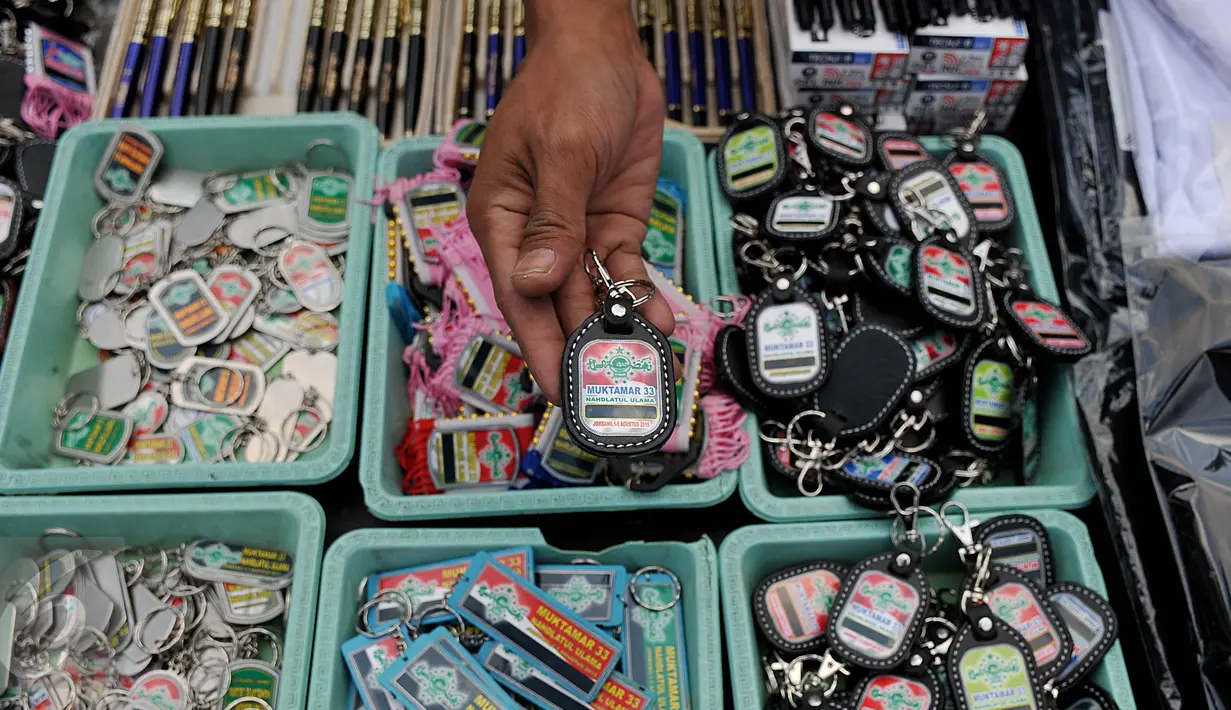 Penjual menunjukkan gantungan kunci berlogo Muktamar ke-33 Nahdlatul Ulama di Jombang, Jawa Timur, Senin (3/8/2015). Pernak-pernik yang dijual yakni kaos, pin, gantungan kunci, dan berbagai produk kerajinan tangan lainnya. (Liputan6.com/Johan Tallo) 