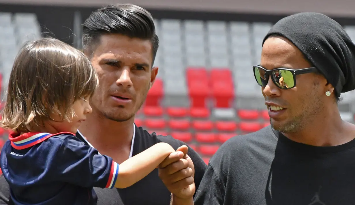 Eks Striker Barcelona, Ronaldinho menyapa gadis kecil sebelum pertandingan persahabatan melawan mantan pemain Kosta Rika di Stadion Nasional di San Jose, (4/8). (AFP Photo/Ezequiel Becerra)