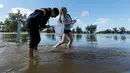 Dua remaja mencari ikan saat banjir melanda Kota Forbes, kawasan pedalaman di New South Wales, Australia, Selasa (27/9). Sungai Lachlan meluap karena tak sanggup menampung air yang berlimpah akibat hujan deras. (REUTERS / Jason Reed)