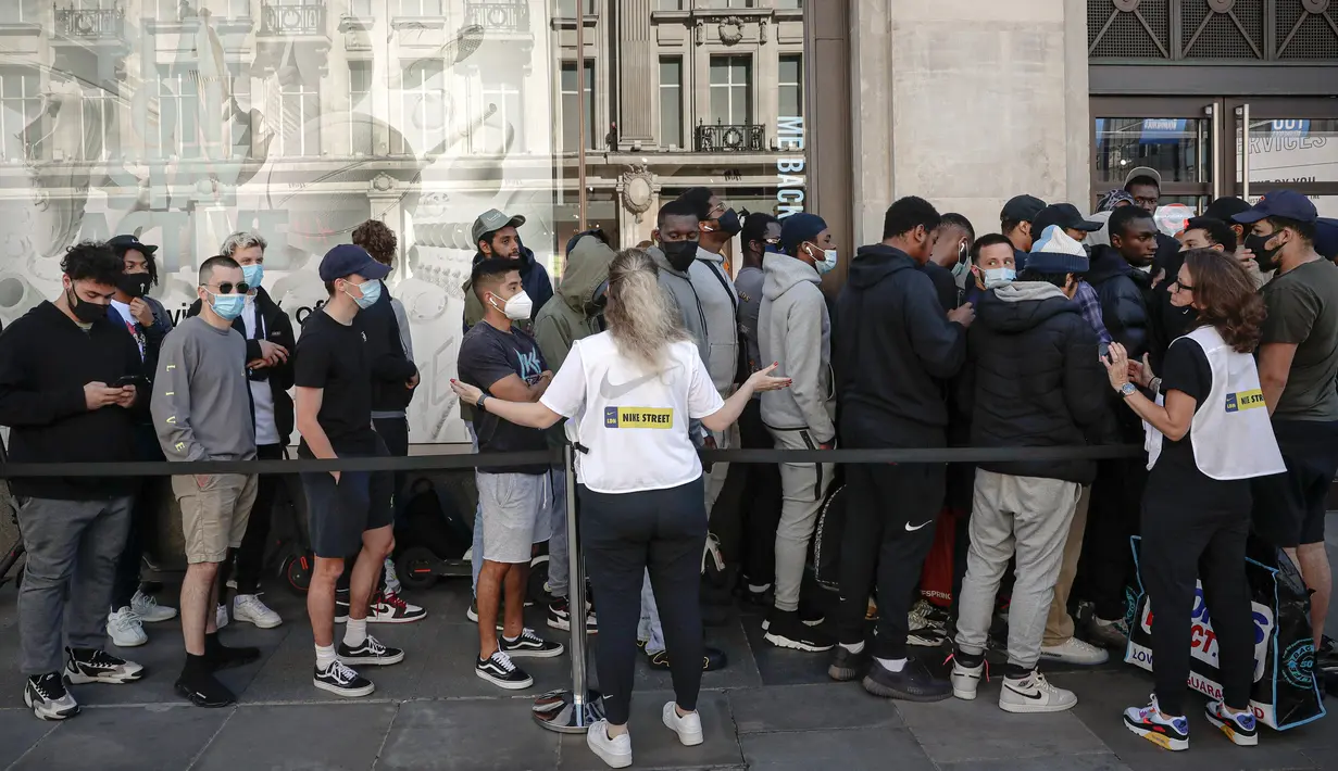Karyawan Nike meminta orang-orang yang antre untuk menjaga jarak di luar toko Niketown di London, Senin (15/6/2020). Antrean panjang terjadi di luar toko-toko yang berada di sejumlah kota di Inggris saat negara itu melakukan pelonggaran lockdown dan mulai membuka pusat perbelanjaan. (AP/Matt Dunham)