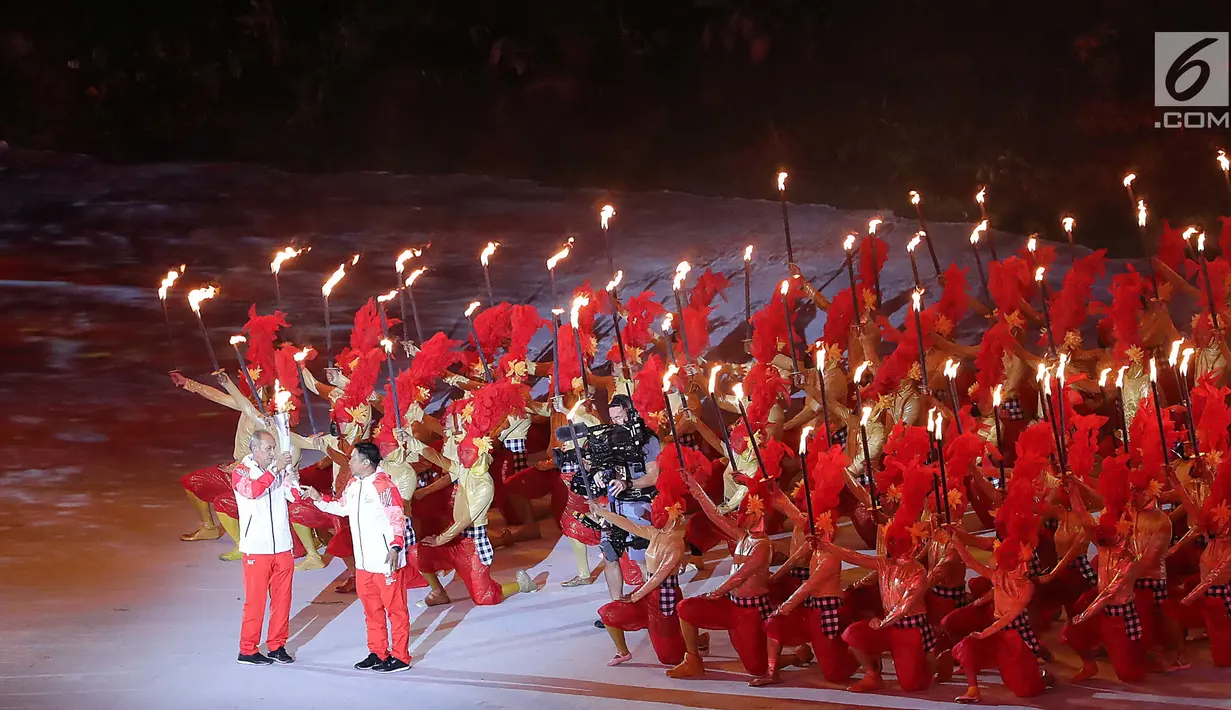 Peraih medali emas Asian Games 1978 dan 1982 Yustedjo Tarik memberi obor Asian Games 2018 kepada peraih medali emas selancar angin Asian Games Busan 2002 I Gusti Made Oka Sulaksana saat pembukaan di SUGBK, Jakarta, Sabtu (18/8). (Liputan.com/Fery Pradolo)