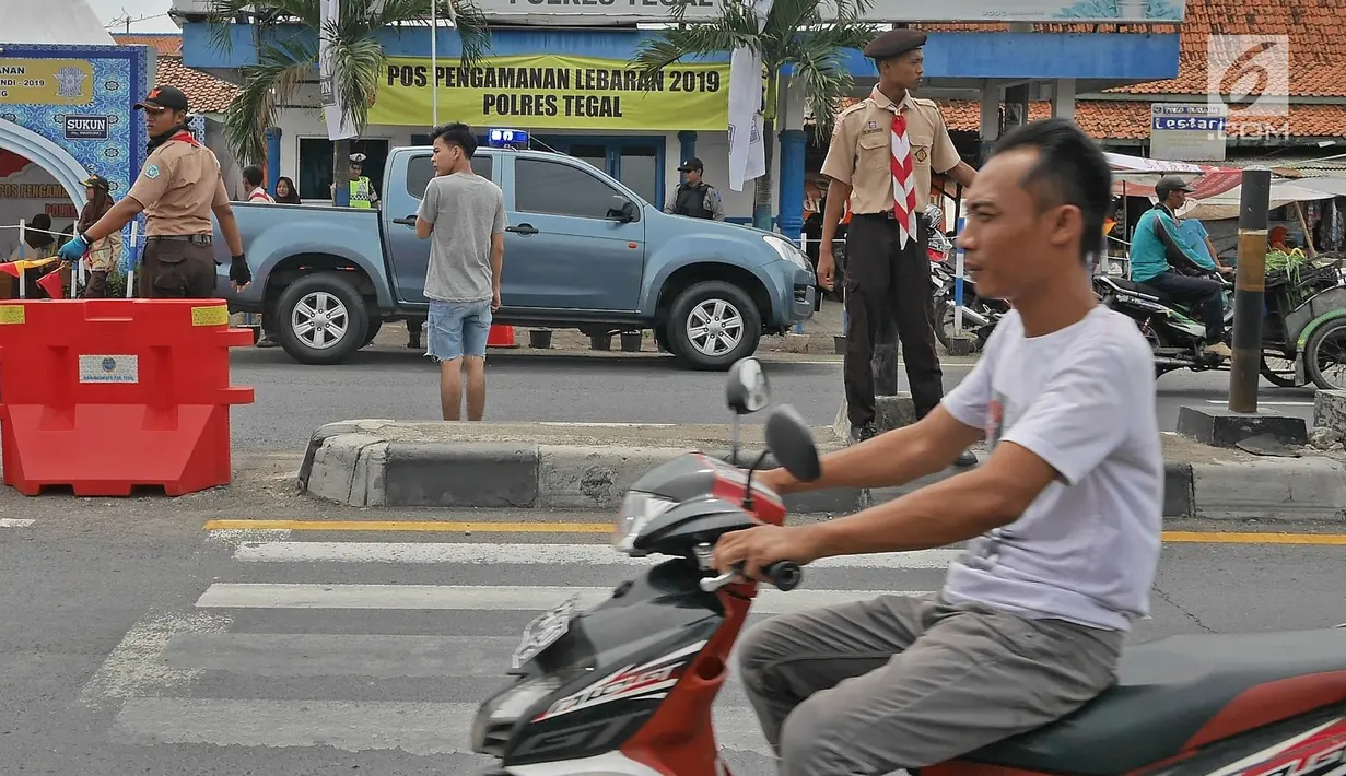 Anggota Pramuka membantu mengatur lalu lintas di jalur mudik kawasan pasar Surodadi, Tegal  Jawa Tengah, Senin (3/6/2019). Puluhan anggota Pramuka  membantu polisi mengatur lalu lintas selama arus mudik maupun arus balik. (Liputan6.com/Herman Zakharia)