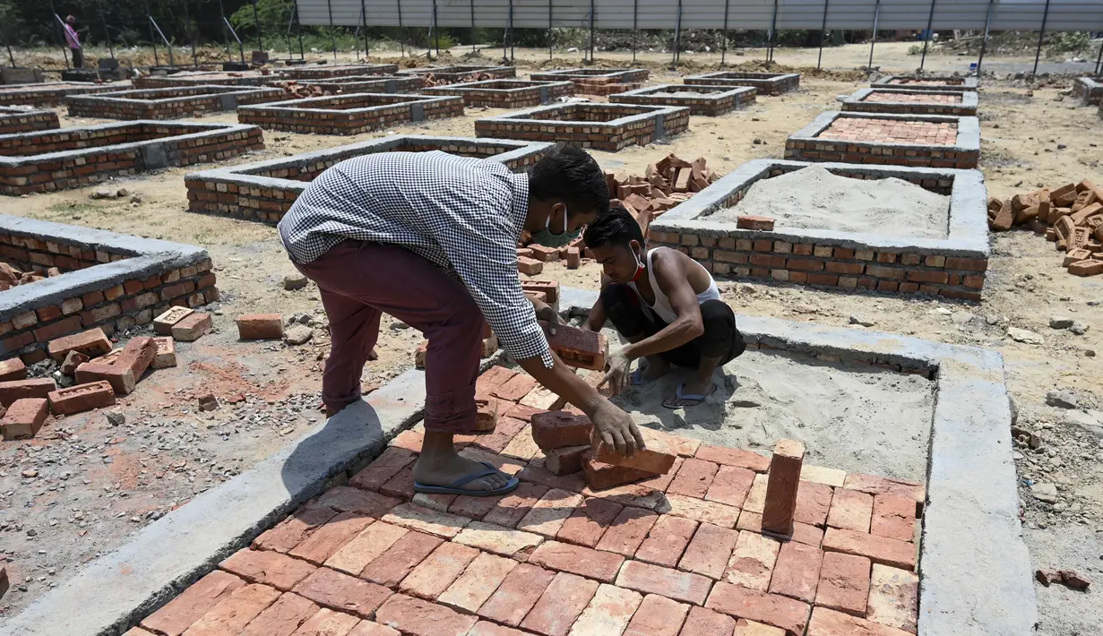 Para buruh bekerja membangun tempat kremasi di ladang kosong di New Delhi, India, Rabu (5/5/2021). Tsunami COVID-19 di India yang telah menembus 20 juta kasus menjadi sorotan dunia. (Money SHARMA/AFP)