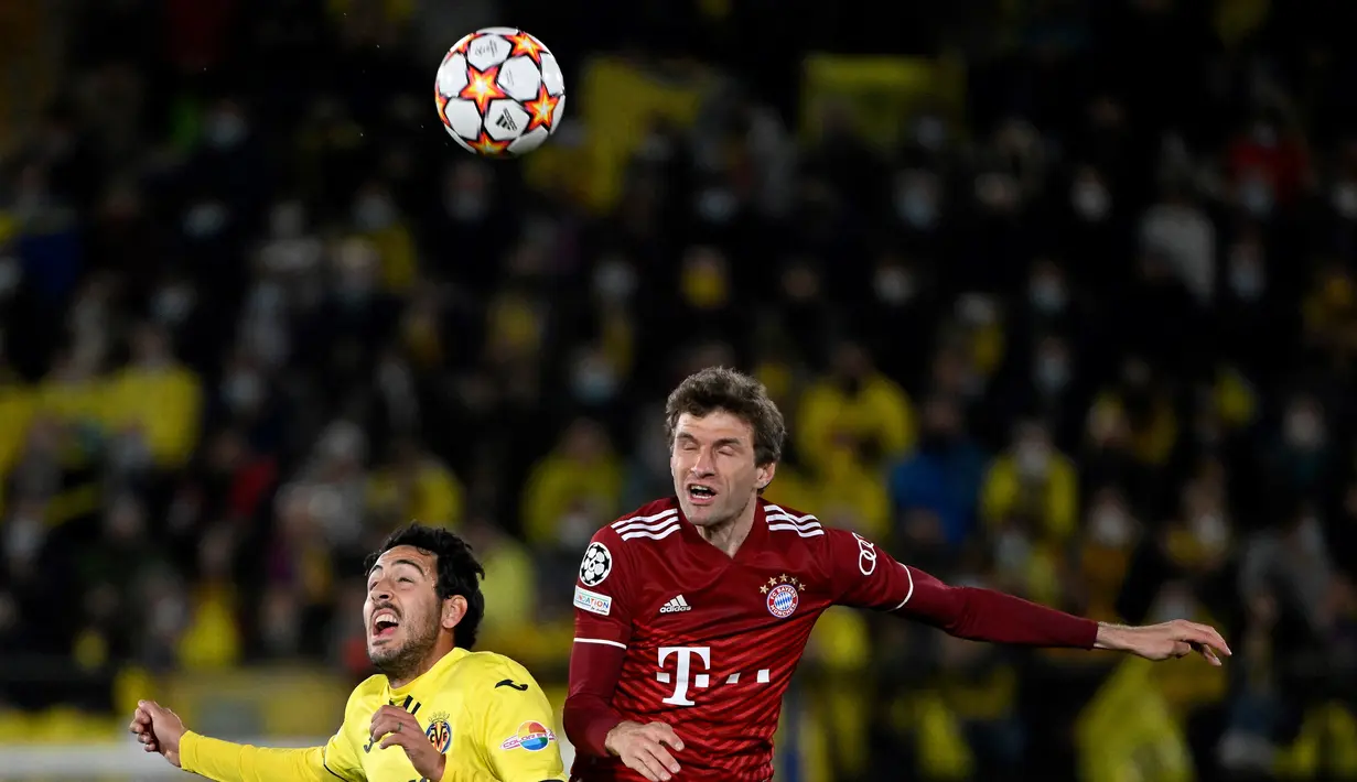 Gelandang Villarreal, Daniel Parejo berebut bola udara dengan penyerang Bayern Munchen, Thomas Mueller pada pertandingan leg pertama perempat final Liga Champions di stadion La Ceramica di Vila-real, Kamis (7/4/2022). Villarreal menang tipis atas Bayern Munchen 1-0. (AFP/Pierre-Philippe Marcou)