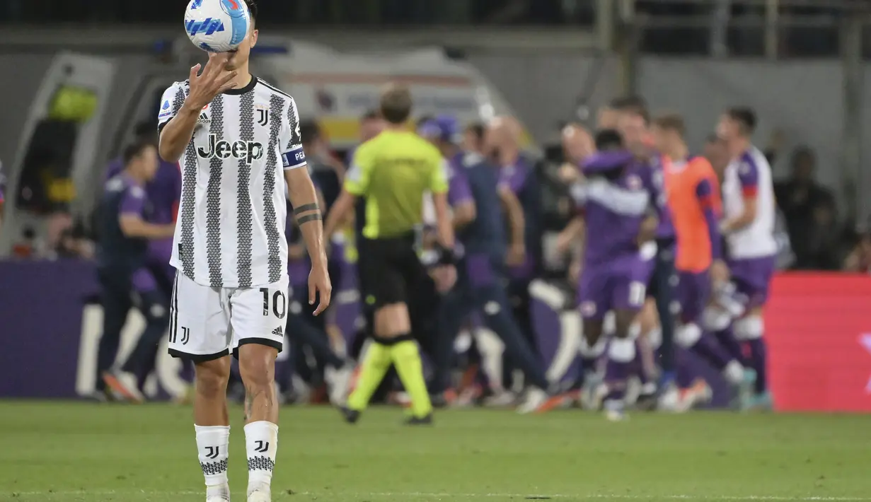 Penyerang Juventus, Paulo Dybala memegang bola saat para pemain Fiorentina melakukan selebrasi selama pertandingan lanjutan Liga Serie A Italia di Florence, Italia, Minggu (22/5/2022). Fiorentina menang atas Juventus dengan skor 2-0. (Alfredo Falcone/LaPresse via AP)