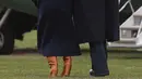Presiden AS Donald Trump merangkul Melania Trump yang hampir terjatuh saat berjalan menuju helikopter kepresidenan di Gedung Putih, Senin (19/3). Melania Trump kehilangan keseimbangan saat mengenakan sepatu berhak 10 cm itu.  (AP/Pablo Martinez Monsivais)