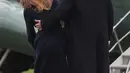 Presiden AS Donald Trump merangkul Melania Trump yang hampir terjatuh saat berjalan menuju helikopter kepresidenan di Gedung Putih, Senin (19/3). Melania Trump kehilangan keseimbangan saat mengenakan sepatu berhak 10 cm itu.  (AP/Pablo Martinez Monsivais)