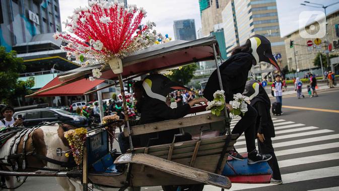 Aktivis Greenpeace turun dari kereta kuda mengenakan topeng penguin saat menggelar aksi dalam car free day di kawasan Thamrin, Jakarta, Minggu (9/2/2020). Mereka mengajak pemerintah untuk berpartisipasi dalam mewujudkan Perjanjian Laut Internasional (Global Ocean Treaty). (Liputan6.com/FaizalFanani)
