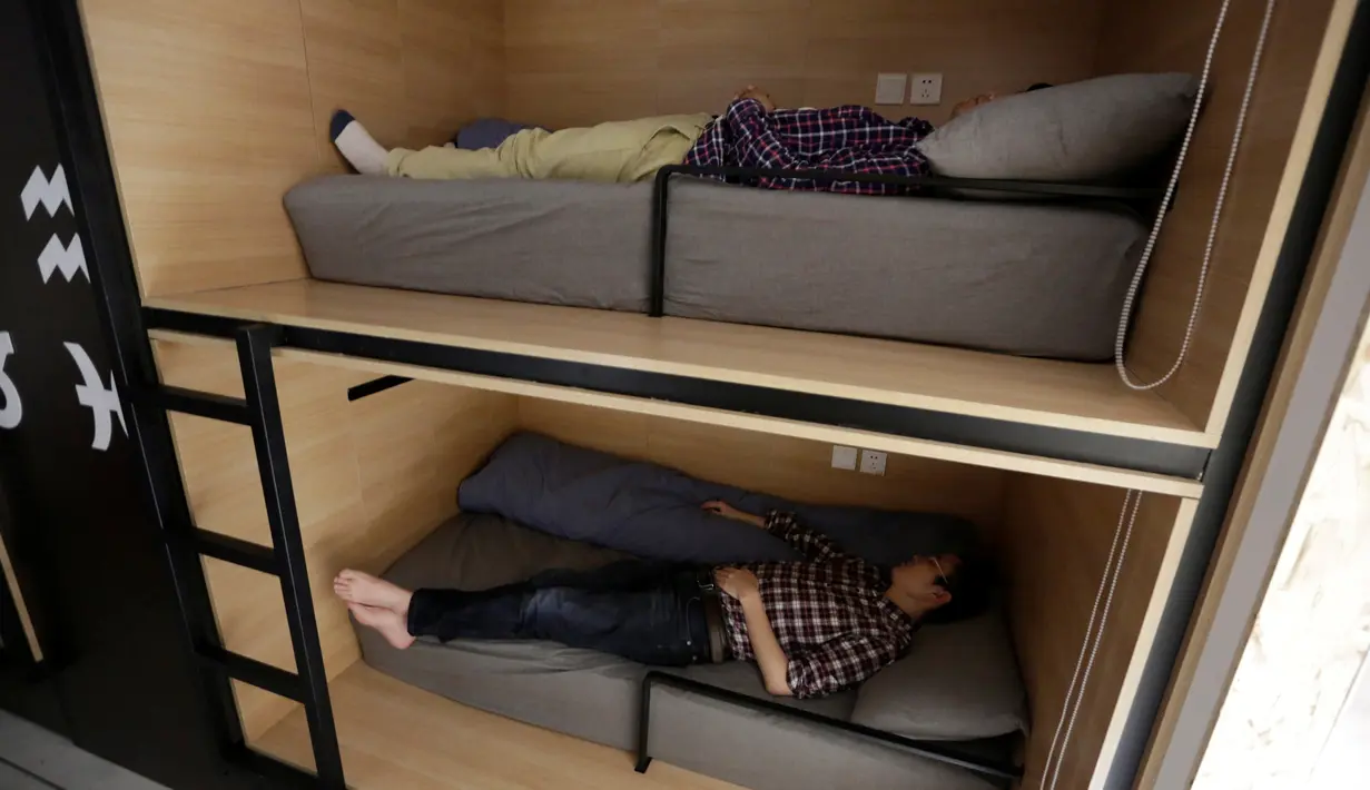 Dua pegawai terlihat tidur siang ditempat tidur pada jam istirahat di kantornya di Beijing, China, (21/4). Sejumlah kantor di Beijing menyediakan ruangan kecil yang dikhususkan untuk tidur siang para pegawainya. (REUTERS/Jason Lee)