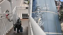 Pejalan kaki melintasi JPO yang tidak terawat di JPO Imigrasi Jakarta Timur, Kamis (17/1). JPO yang berada di depan Kantor Imigrasi Jakarta Timur dalam kondisi tidak terawat, seperti atap yang sudah rusak dan penuh coretan. (Merdeka.com/Iqbal S. Nugroho)