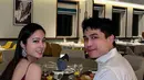Nong Poy tampil dengan dress satin spaghetti strap warna maroon. Sang suami tampil mengenakan kemeja lengan panjang putih. [@poydtreechada]