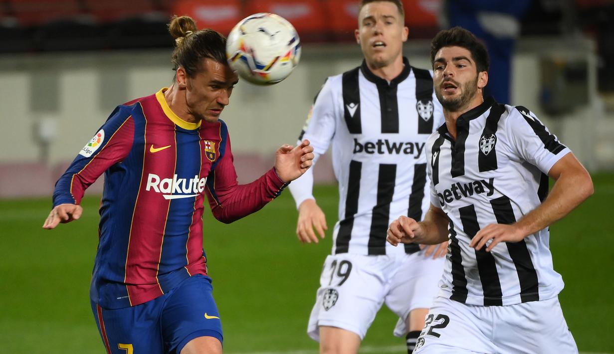 Penyerang Barcelona, Antoine Griezmann, menyundul bola saat melawan Levante pada laga Liga Spanyol di Stadion Camp Nou, Senin (14/12/2020). Barcelona menang dengan skor 1-0. (AFP/Lluis Gene)