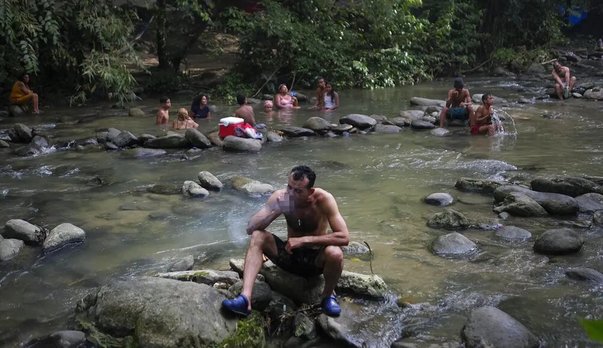 Seorang pengikut aliran sesat Maria Lionza merokok tembakau di sungai di Gunung Sorte, Yaracuy, Venezuela, 11 Oktober 2021. Ritual ini digelar satu tahun setelah ziarah tahunan dibatalkan karena pembatasan COVID-19. (AP Photo/Matias Delacroix)