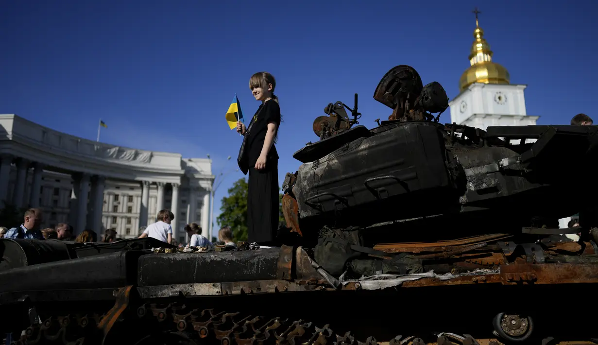 Seorang gadis berdiri di atas tank Rusia yang hancur yang ditempatkan sebagai simbol perang selama perayaan Hari Kiev di Kiev, Ukraina, Minggu (29/5/2022). Ibu kota Ukraina merayakan ulang tahun pendiriannya setiap Minggu terakhir bulan Mei. Kiev merayakan peringatan 1540 tahun pendiriannya, di mana tahun ini dirayakan di bawah darurat militer. (AP Photo/Natacha Pisarenko)