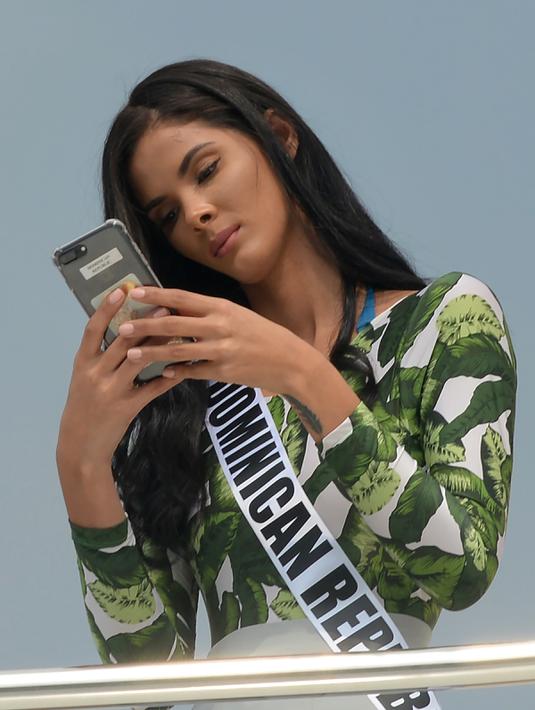 Kontestan asal Republik Dominika, Rosalba Abreu bermain ponsel di atas kapal pesiar saat bertamasya ke sebuah resor wisata pantai di Manila, Filipina (19/1). (AFP Photo/Ted Aljibe)