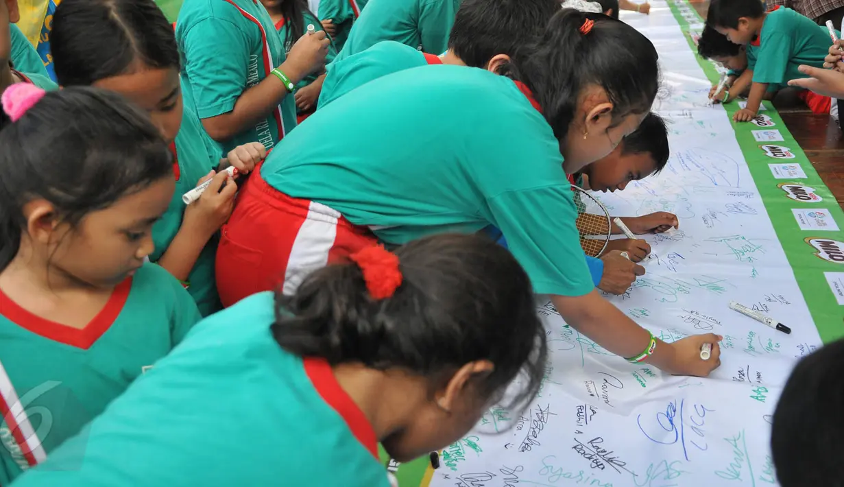 Puluhan murid SD membubuhkan tanda tangan mereka pada sebuah spanduk, Jakarta, Kamis (28/5/2015). Gerakan ini bertujuan untuk memberi dukungan moril bagi atlet Indonesia yang berlaga di Sea Games 2015 Singapura. (Liputan6.com/Herman Zakharia)