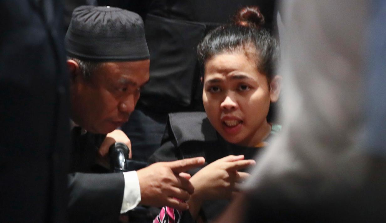 Tersangka kasus pembunuhan Kim Jong-nam, Siti Aisyah berbicara dengan seorang penerjemah saat melakukan reka ulang kejadian di Bandara Internasional Kuala Lumpur, Selasa (24/10). Siti terlihat dikawal ketat polisi bersenjata lengkap. (AP/Sadiq Asyraf)