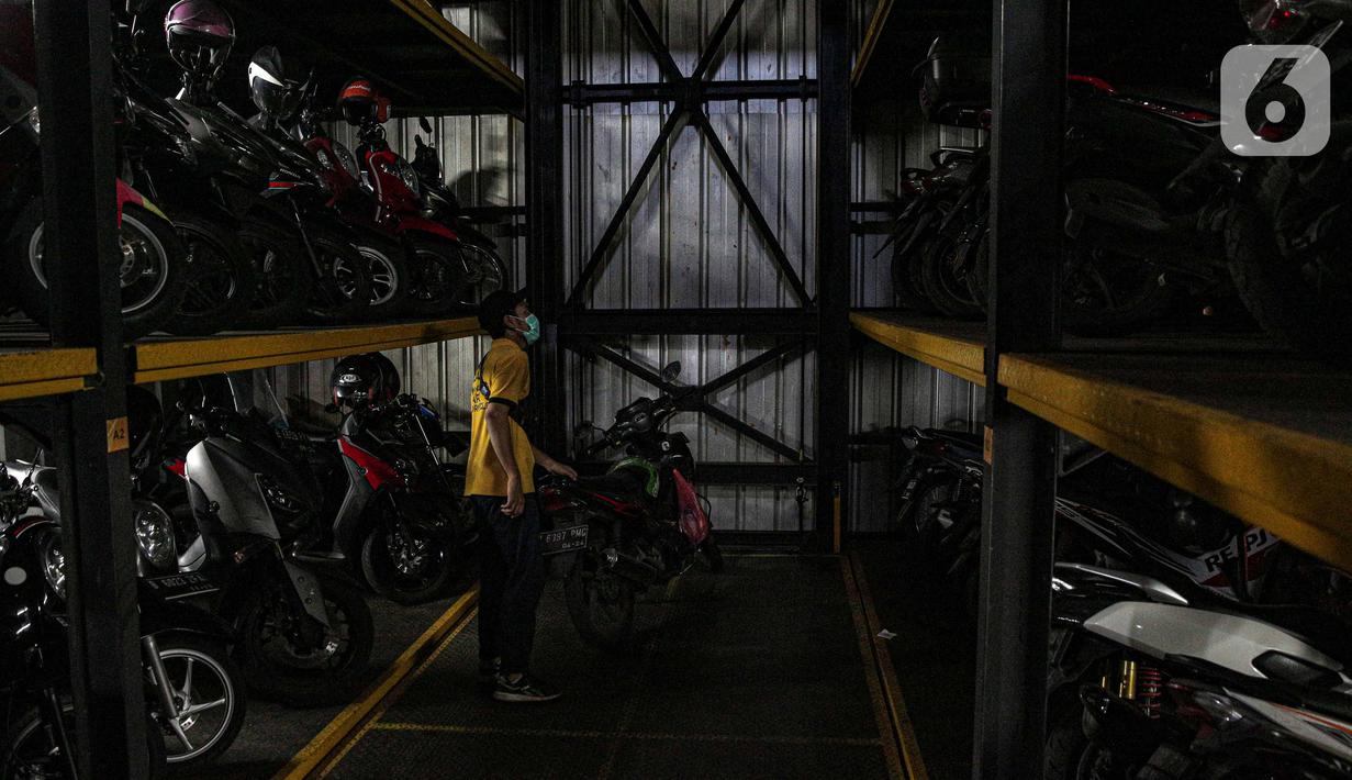 Pekerja menurunkan sepeda motor di Soul Parking, Kebon Kacang, Jakarta, Jumat (21/1/2022). Tempat parkir vertikal tersebut menerapkan sistem teknologi Compact Motor Storage atau sistem rak bersusun dengan lift barang. (Liputan6.com/Faizal Fanani)