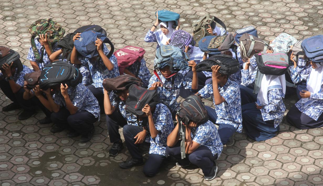Para murid menggunakan tas untuk pelindung dalam latihan tsunami di Meulaboh (5/9). Sebanyak 24 negara yang berbatasan dengan Samudra Hindia, dari Australia hingga Yaman, mengambil bagian dalam latihan kesiapsiagaan bencana dua tahunan. (AFP Photo/Januar)