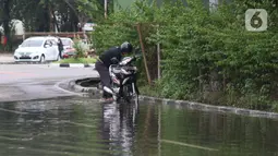 Pengendara memanfaatkan genangan air untuk mencuci kendaraan di Jalan HBR Motik Kemayoran, Jakarta, Selasa (25/2/2020). Hujan yang mengguyur Jakarta sejak Senin (24/2) malam membuat sejumlah kali meluap dan menyebabkan banjir. (Liputan6.com/Helmi Fithriansyah)