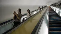 Komuter melihat ponselnya sambil menggunakan eskalator di stasiun kereta bawah tanah Pyongyang, Korea Utara, 6 September 2018. Ternyata kebiasaan melihat gawai di kereta pun tidak jauh berbeda, meskipun tidak banyak. (AFP / Ed JONES)