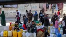 Orang-orang yang terlantar akibat perang menunggu dengan wadah air untuk mengisi persediaan mereka dari tangki air di kamp penampungan, Khan Yunis, Jalur Gaza Selatan pada 6 Juni 2026. (Bashar Taleb/AFP)